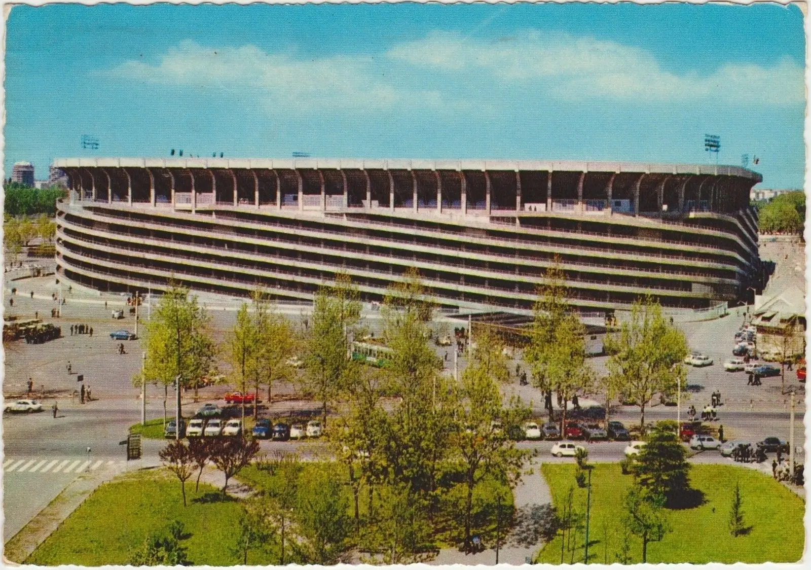 Alberi in primo piano, secondo anello compiuto, 1968–69. Il Palasport non c’è ancora, aprirà il 31 gennaio 1976. Dal semaforo di via Novara lo stadio non si vede intero: si vedono le torri, dopo.